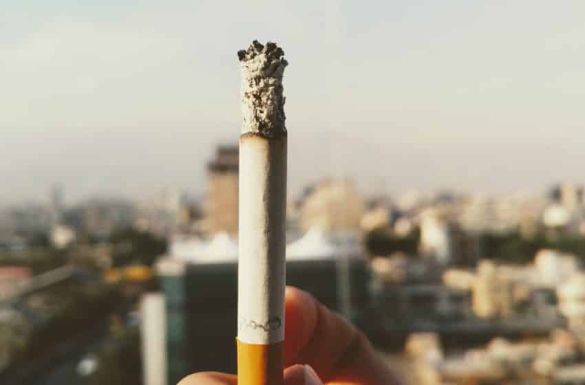 A smoker holding a lit cigarette up (Unsplash | Eanlami)